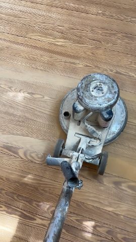 A floor sander is on a hardwood floor.